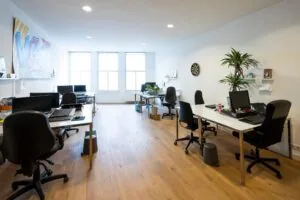 Modern kantoor met houten vloer, meerdere werkplekken en grote ramen aan de Nieuwezijds Voorburgwal.